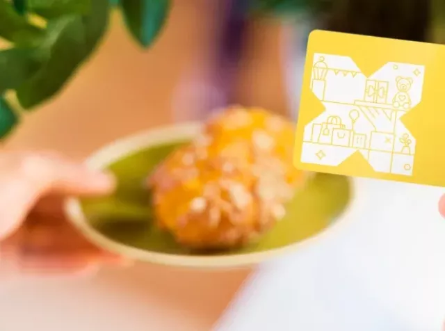 Eine Hand mit der Pluxee Benefits Card und ein Stück Kuchen