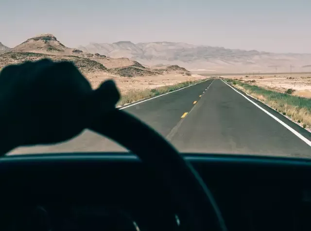 Eine Person fährt ein Auto auf einer Wüstenstraße und erhält durch den Pluxee Benefit Auto Abo & Leasing Zuschüsse für E-Mobilität.
