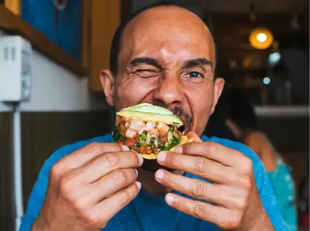 Ein Mann, der den Pluxee Essenszuschuss in Anspruch nimmt, verspeist genussvoll ein Sandwich.