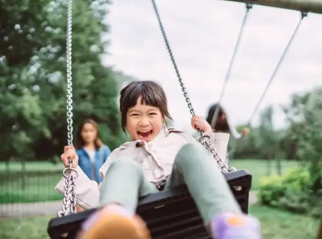 Auf der Schaukel lachend, zeigt uns das kleine Mädchen, wie wichtig es ist, Zeit mit der Familie zu verbringen. Der Pluxee KiTa Zuschuss unterstützt Eltern dabei, Familie und Beruf miteinander zu vereinbaren.