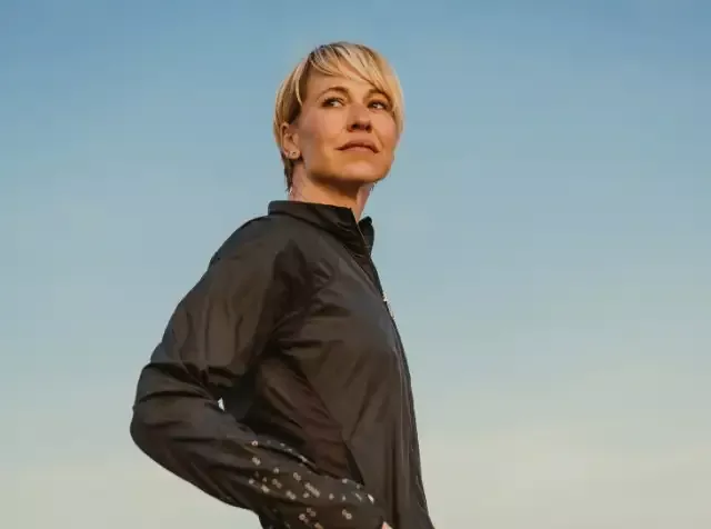 Eine Frau in Laufjacke am Strand genießt die frische Luft und freut sich über den Zusatz zur gesetzlichen Krankenversicherung durch ihren Arbeitgeber, der sie bestens versorgt.