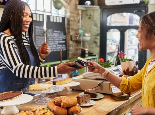 Eine Frau bezahlt in einer Bäckerei mit ihrer Benefits Card von Pluxee. 