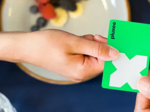 Zwei Menschen mit grüner Pluxee Card die überreicht wird.