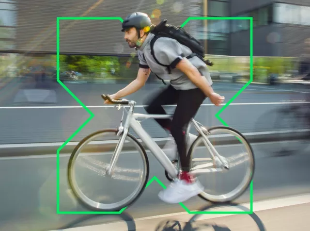 Pluxee Bike – Mann mit Helm fährt zügig mit einem modernen geleasten Dienstfahrrad durch die Stadt