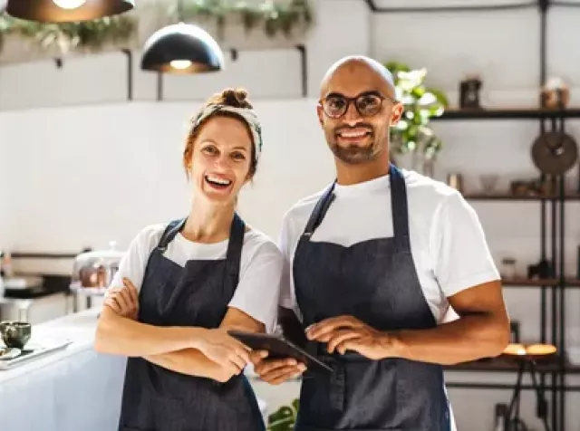 Zwei Gastronomen in blauen Schürzen freuen sich über Vorteile der Entegra-Pluxee Partnerschaft.