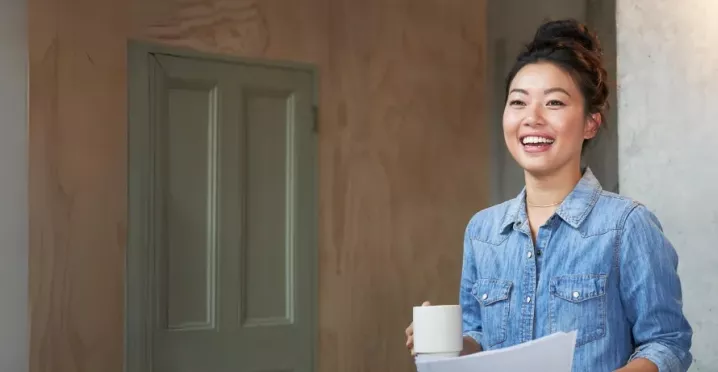Jung Frau mit hochgesteckten Haaren hält eine Kaffeetassen in der Hand