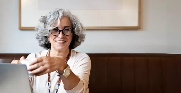 Frau mit grauen Haaren und dunkler Brille lacht 