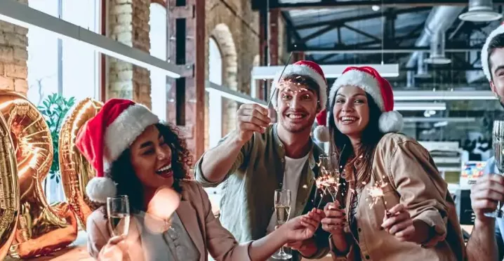 Ein Team von Mitarbeitenden in Weihnachtsstimmung in einem Loftbüro mit Weihnachtsdeko