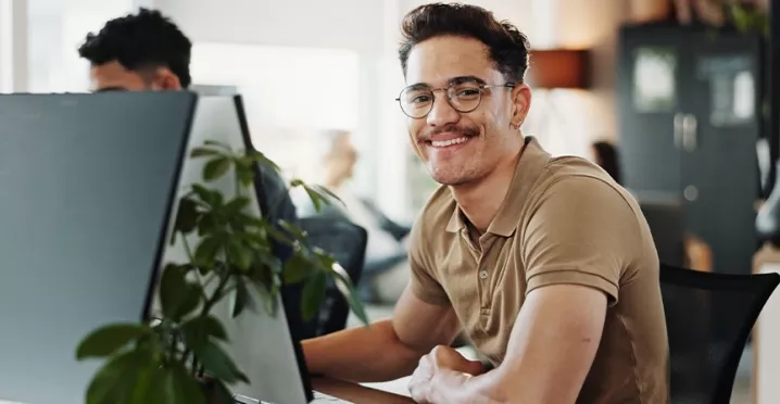 Freundlicher HR-Mitarbeiter arbeitet am Computer und unterstützt Mitarbeitende.