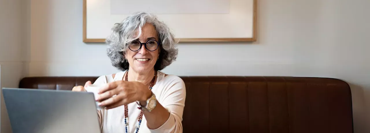 Frau mit grauen Haaren und dunkler Brille lacht 