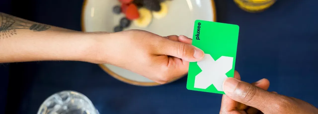 Zwei Menschen mit grüner Pluxee Card die überreicht wird.