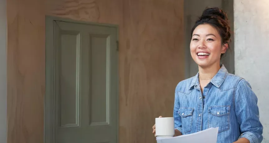 Jung Frau mit hochgesteckten Haaren hält eine Kaffeetassen in der Hand