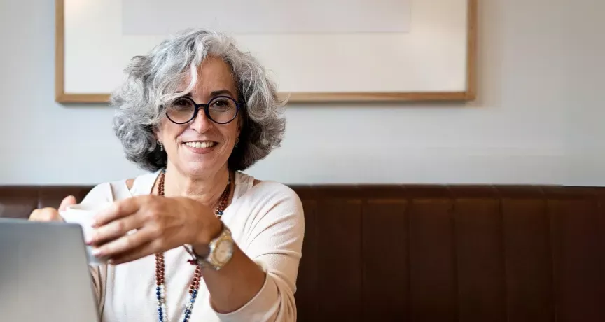 Frau mit grauen Haaren und dunkler Brille lacht 
