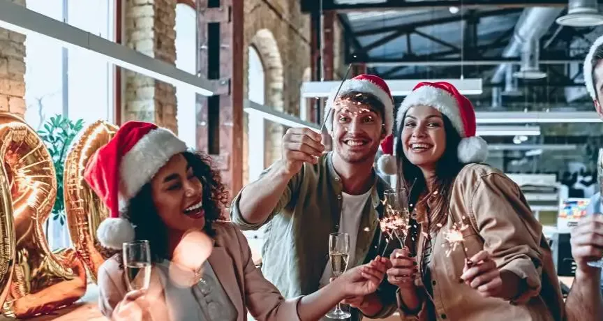 Ein Team von Mitarbeitenden in Weihnachtsstimmung in einem Loftbüro mit Weihnachtsdeko