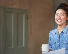 Jung Frau mit hochgesteckten Haaren hält eine Kaffeetassen in der Hand