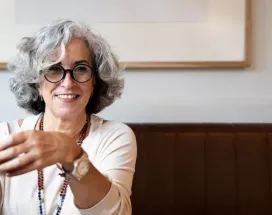 Frau mit grauen Haaren und dunkler Brille lacht 