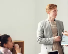 Zwei Menschen unterhalten sich vor einer Seminargruppe. 