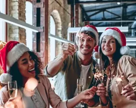 Ein Team von Mitarbeitenden in Weihnachtsstimmung in einem Loftbüro mit Weihnachtsdeko