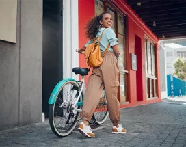 Junge Frau mit schwarzen lockigen Haaren fährt lächelnd auf einem türkisfarbenen Hollandrad – Symbolbild für modernes Bikeleasing und nachhaltige Mobilität.