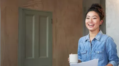 Jung Frau mit hochgesteckten Haaren hält eine Kaffeetassen in der Hand