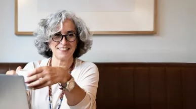 Frau mit grauen Haaren und dunkler Brille lacht 