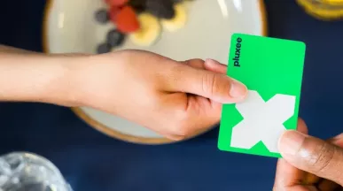 Zwei Menschen mit grüner Pluxee Card die überreicht wird.