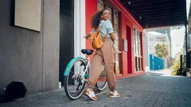 Junge Frau mit schwarzen lockigen Haaren fährt lächelnd auf einem türkisfarbenen Hollandrad – Symbolbild für modernes Bikeleasing und nachhaltige Mobilität.