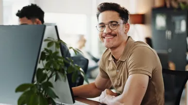 Freundlicher HR-Mitarbeiter arbeitet am Computer und unterstützt Mitarbeitende.
