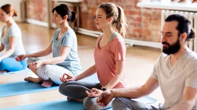 Männer und Frauen meditieren gemeinsam im Pilatesstudio zur Förderung von Wohlbefinden und Balance.