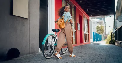 Junge Frau mit schwarzen lockigen Haaren fährt lächelnd auf einem türkisfarbenen Hollandrad – Symbolbild für modernes Bikeleasing und nachhaltige Mobilität.