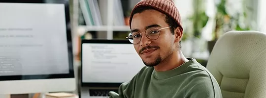 Junger HR-Mitarbeiter sitzt am Computer und nutzt den Pluxee Benefits Guide.