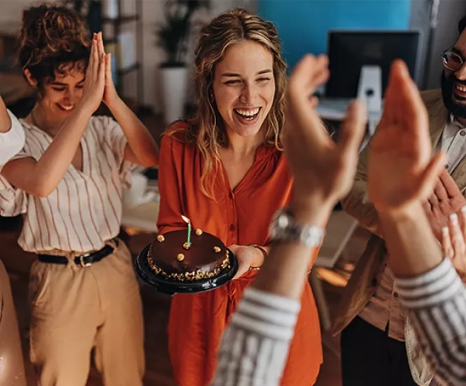 Frau lachend mit Schokotorte in der Hand, Geburstag feiernd
